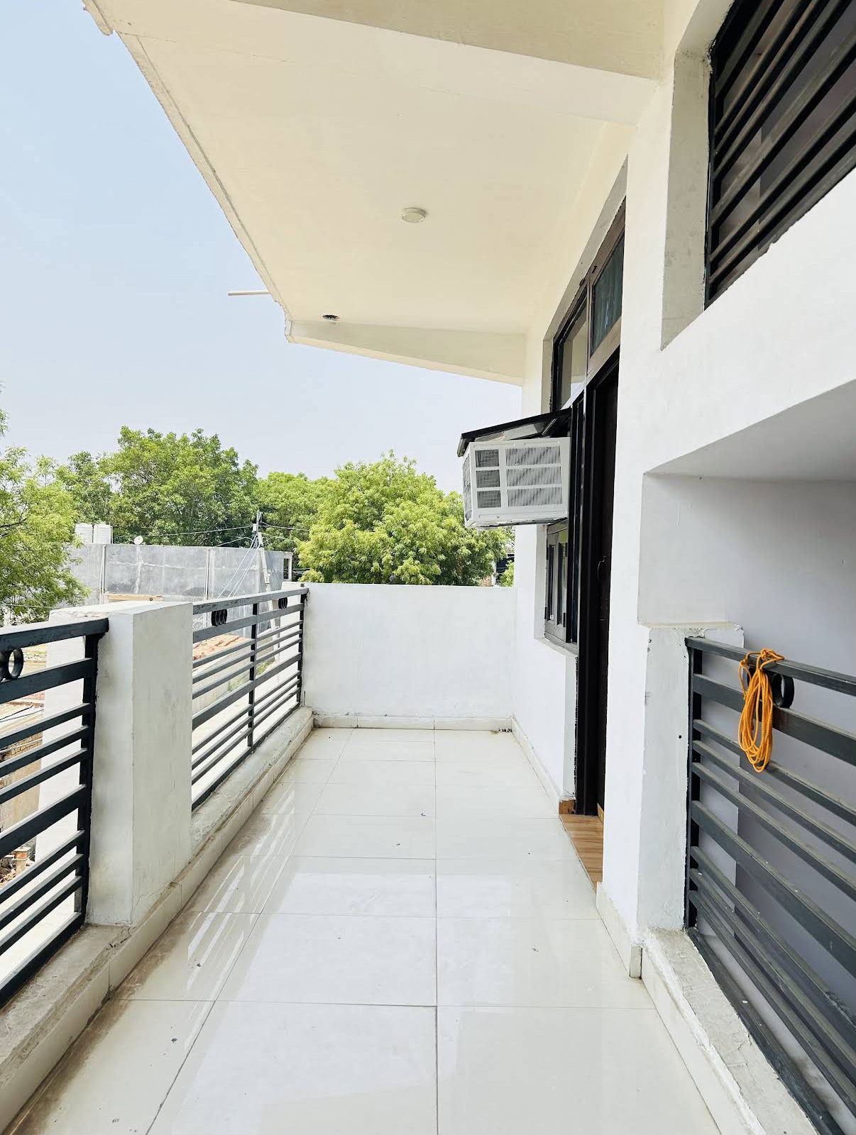 Tiled balcony outside the rooms, with trees beyond